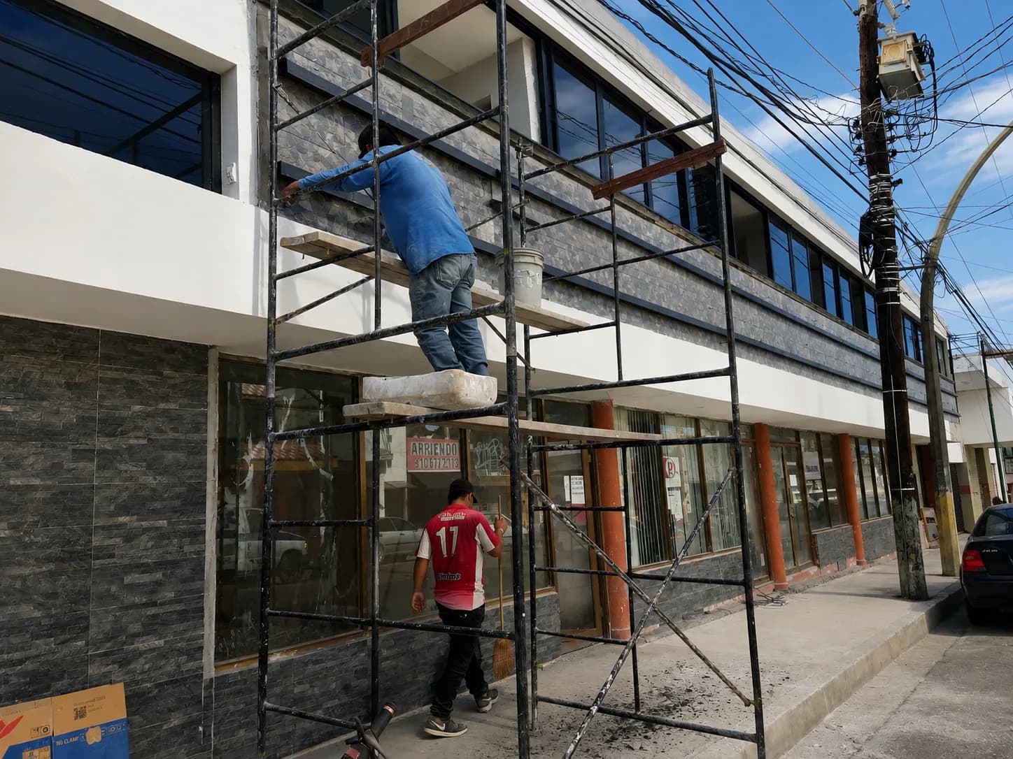 Trabajos de fachada sobre andamio en un edificio de locales comerciales